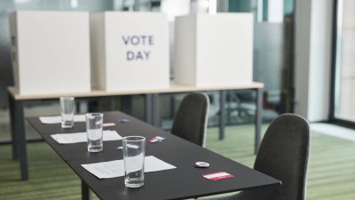Seção eleitoral preparada em uma sala, com mesas, cadeiras e cabines de votação.