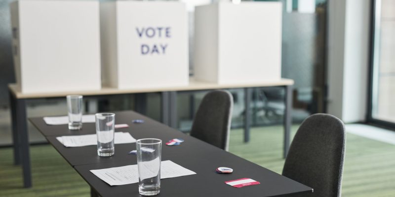 Seção eleitoral preparada em uma sala, com mesas, cadeiras e cabines de votação.