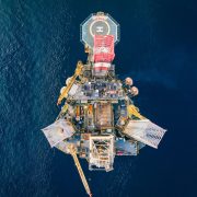 Vista aérea de uma plataforma de petróleo offshore cercada pelo mar azul.