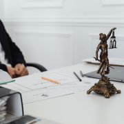 Mesa de trabalho jurídico com documentos, laptop e uma estátua da Justiça.