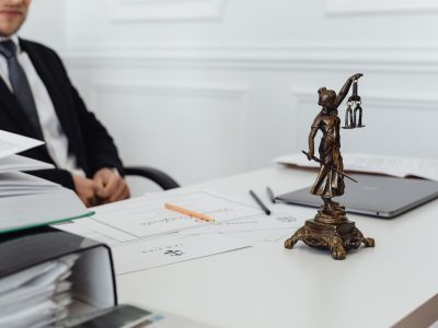 Mesa de trabalho jurídico com documentos, laptop e uma estátua da Justiça.